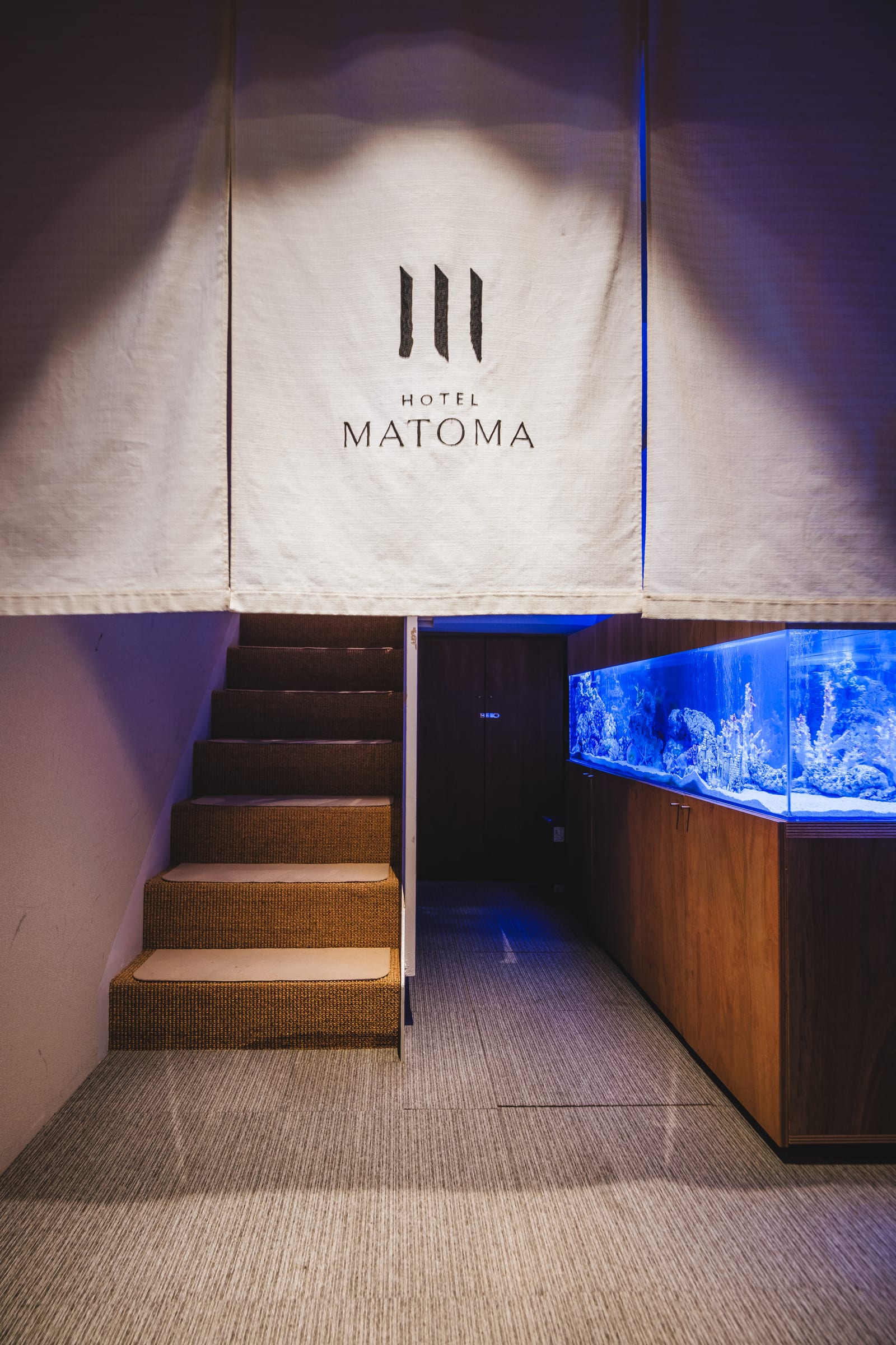暖簾と階段、水槽のある HOTEL MATOMA のエントランス