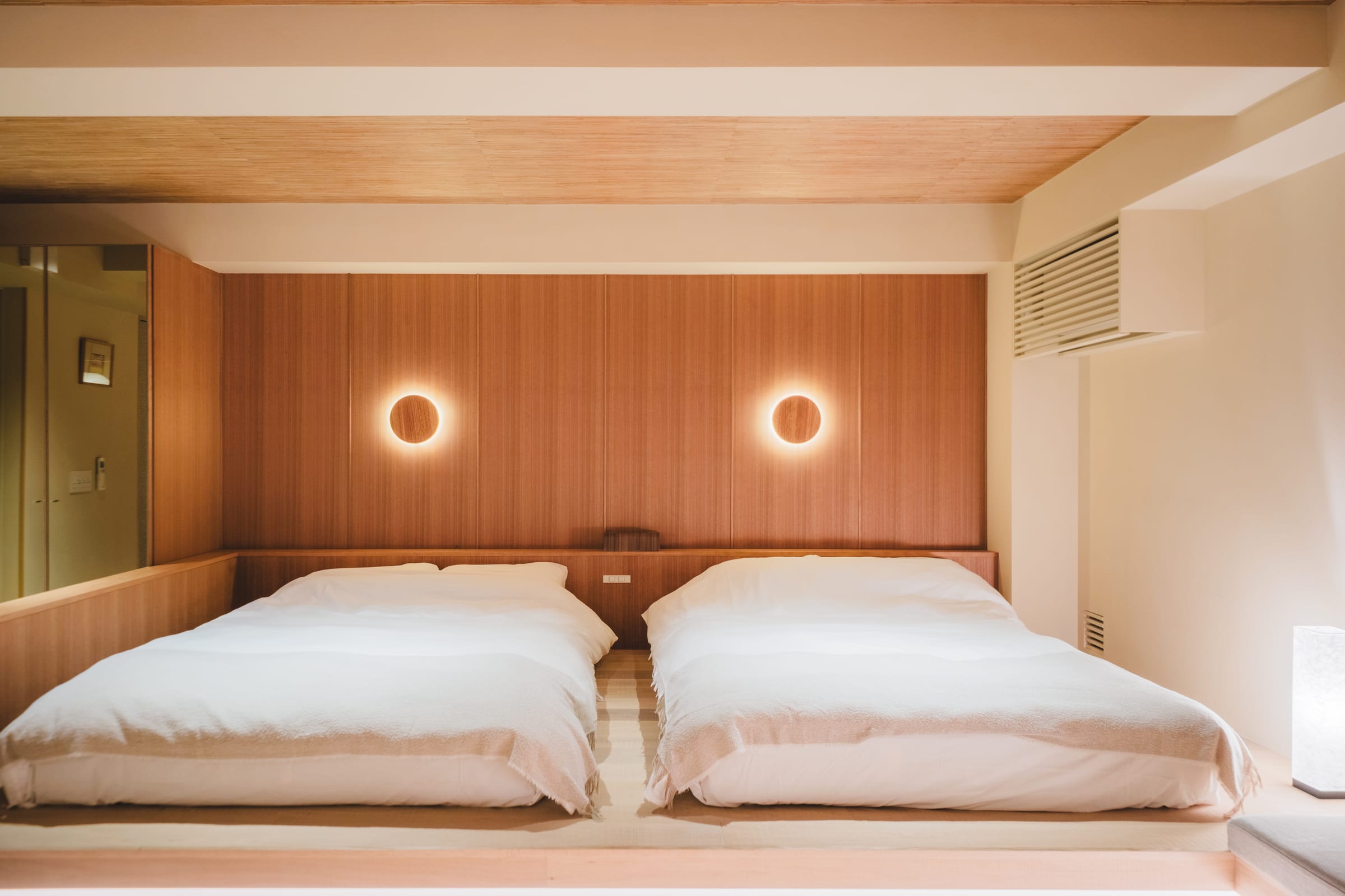 木の壁と丸い照明が印象的な HOTEL MATOMA のベッドルーム